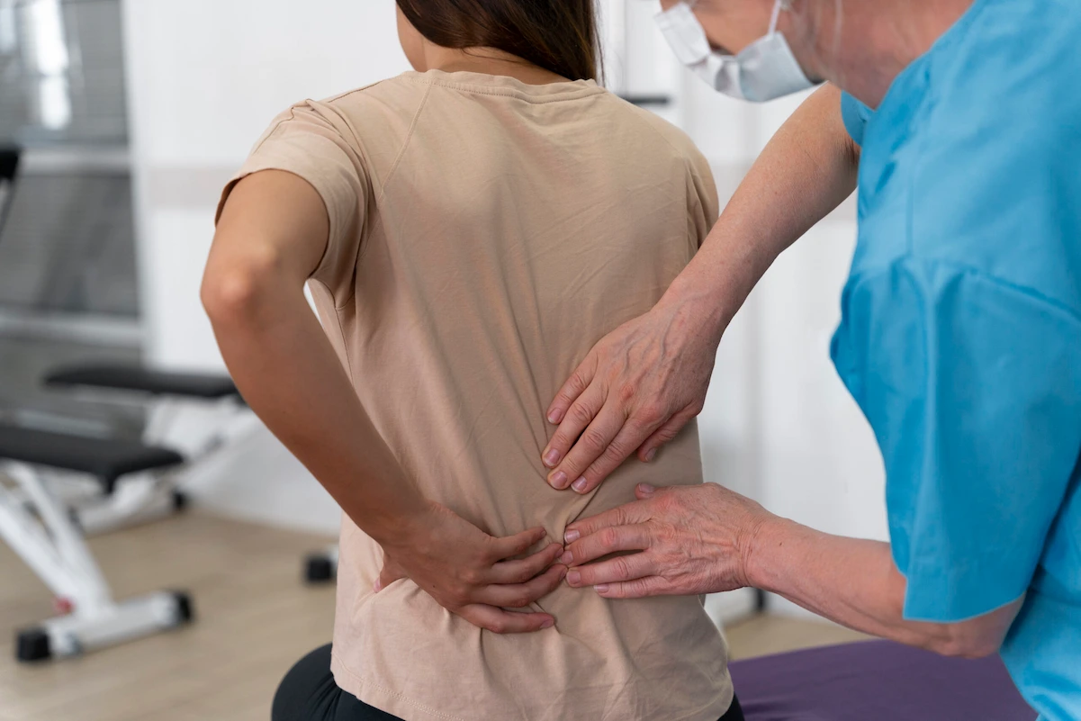 Chiropractor assessing lower back of female patient