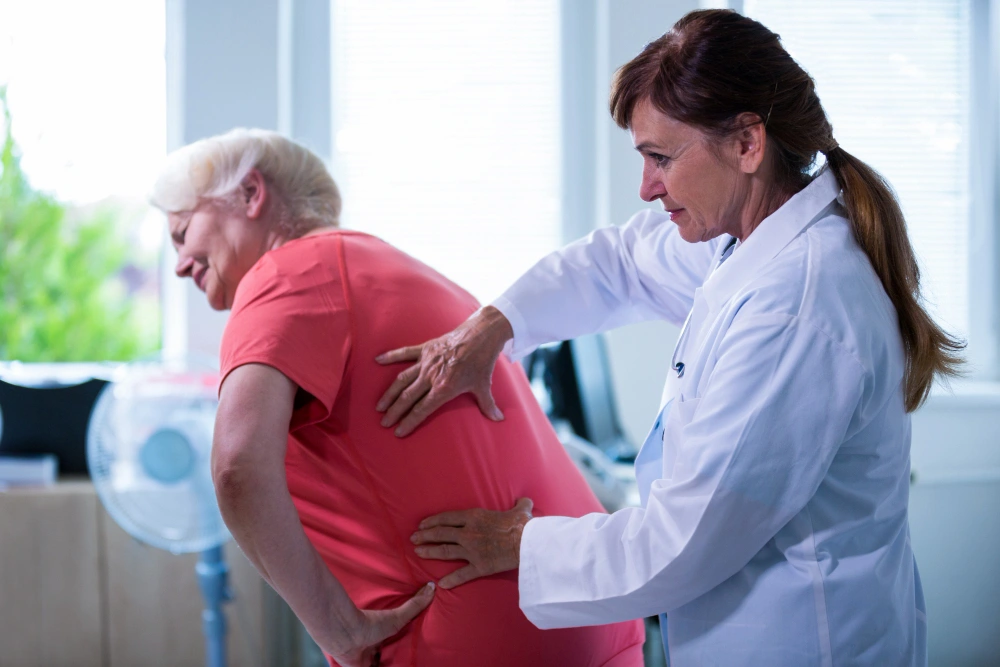 Chiropractor assessing elderly woman with back pain