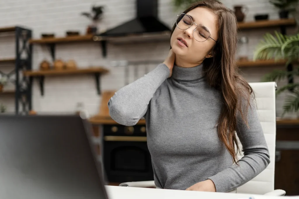Female wearing glasses holding her neck in pain