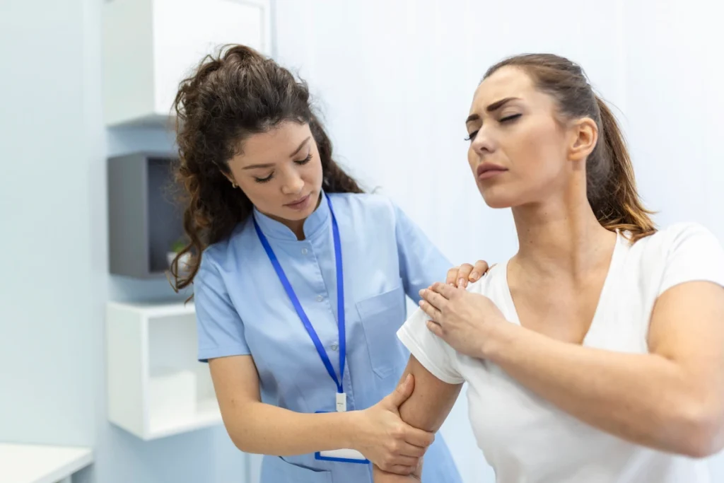 Chiropractor assessing the shoulder of a female patient while she seems in pain