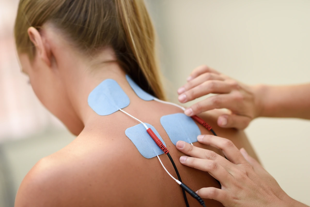 Electrical stimulation being applied to a woman's back for chiropractic care