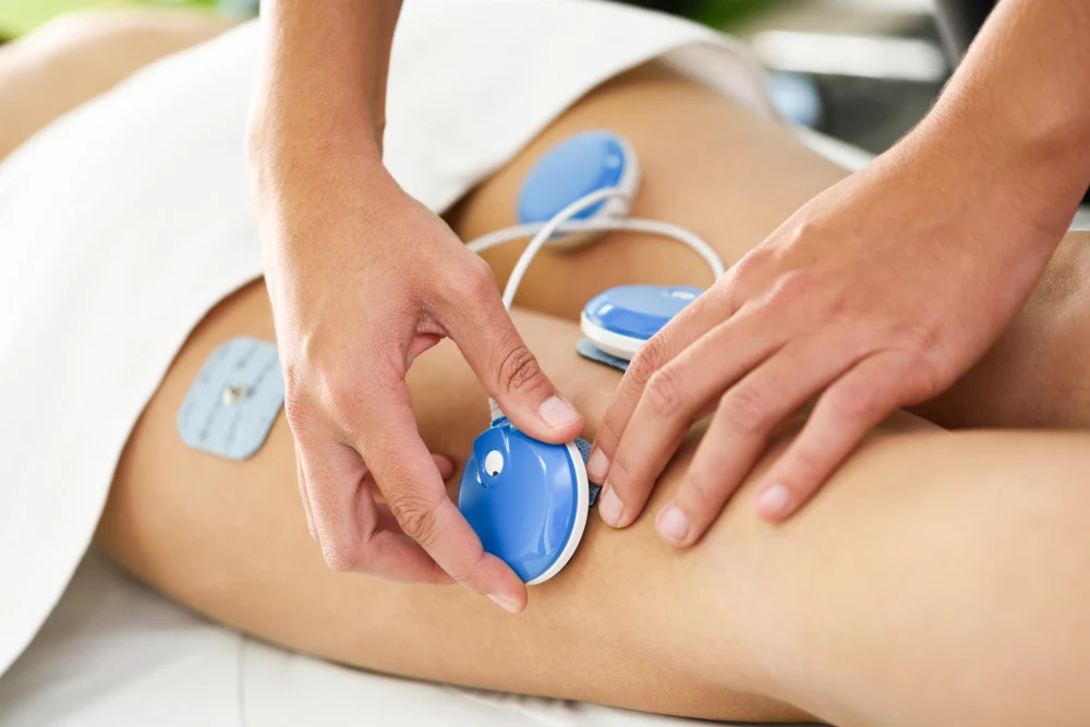 Electro stimulation in physical therapy to a young woman leg