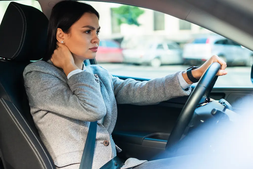 Driver experiencing back pain during long commute due to poor posture and prolonged sitting