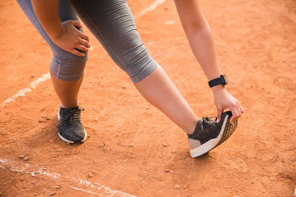 Person looking at footwear while experiencing leg or lower body discomfort
